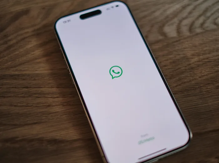 Smartphone posé sur une table en bois, affichant l'icône WhatsApp