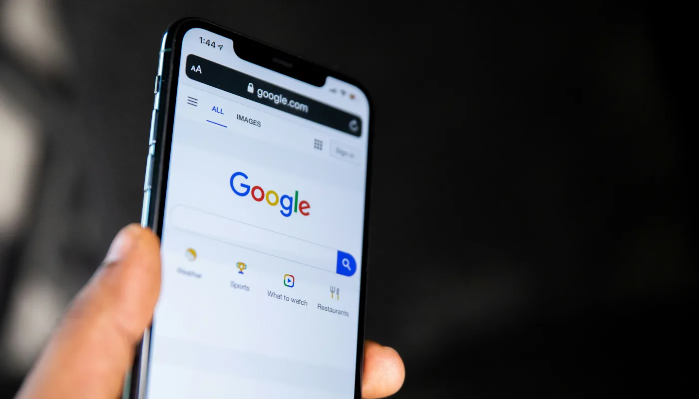 Main tenant un smartphone affichant la page d'accueil Google, prête à taper une recherche