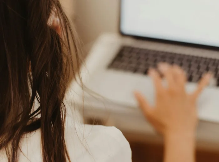 Mains tapant une réponse posée sur le clavier d'un ordinateur portable