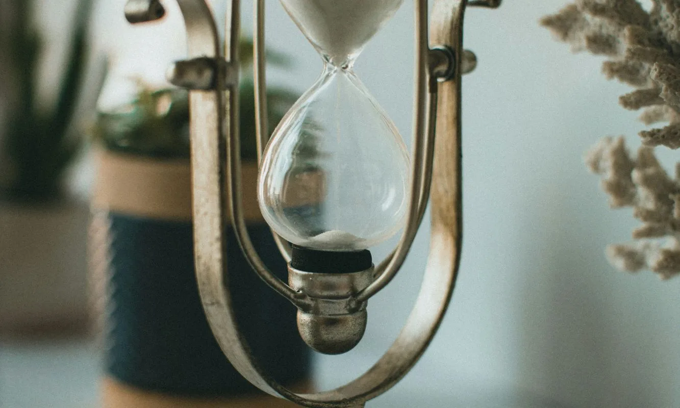 Sablier ancien posé sur une table, symbolisant le temps qui passe