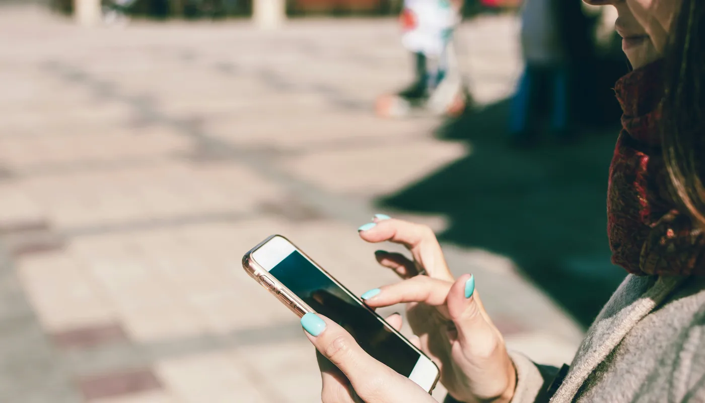 Personne consultant un site sur son smartphone en extérieur, pressée